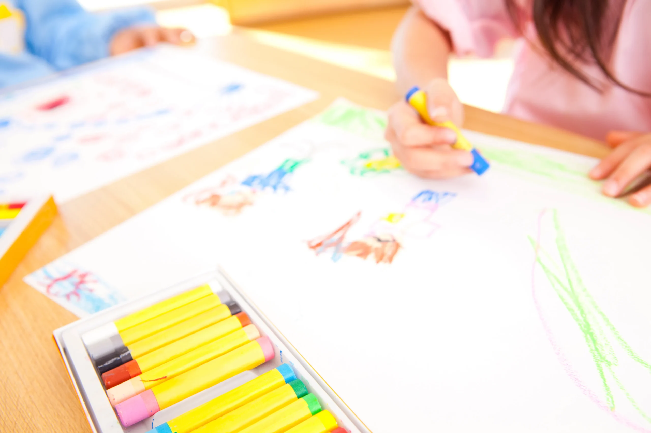クレヨンで絵を描く幼稚園児の手元