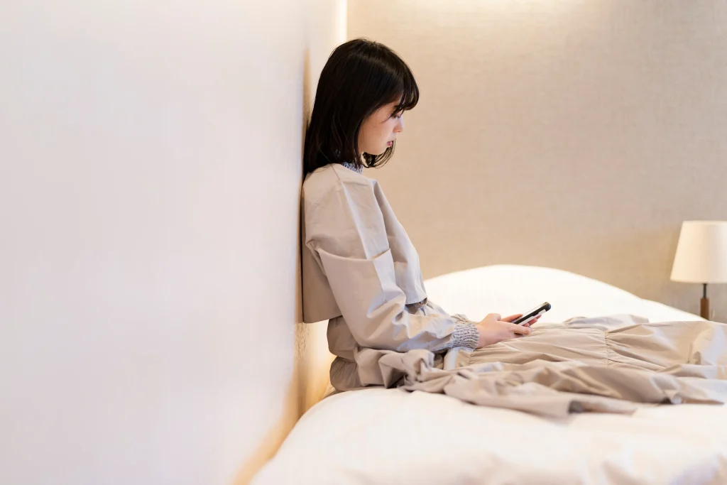 寝室でスマホを眺める