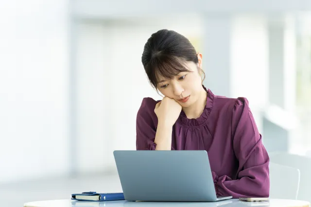 パソコンを使いながら考える女性